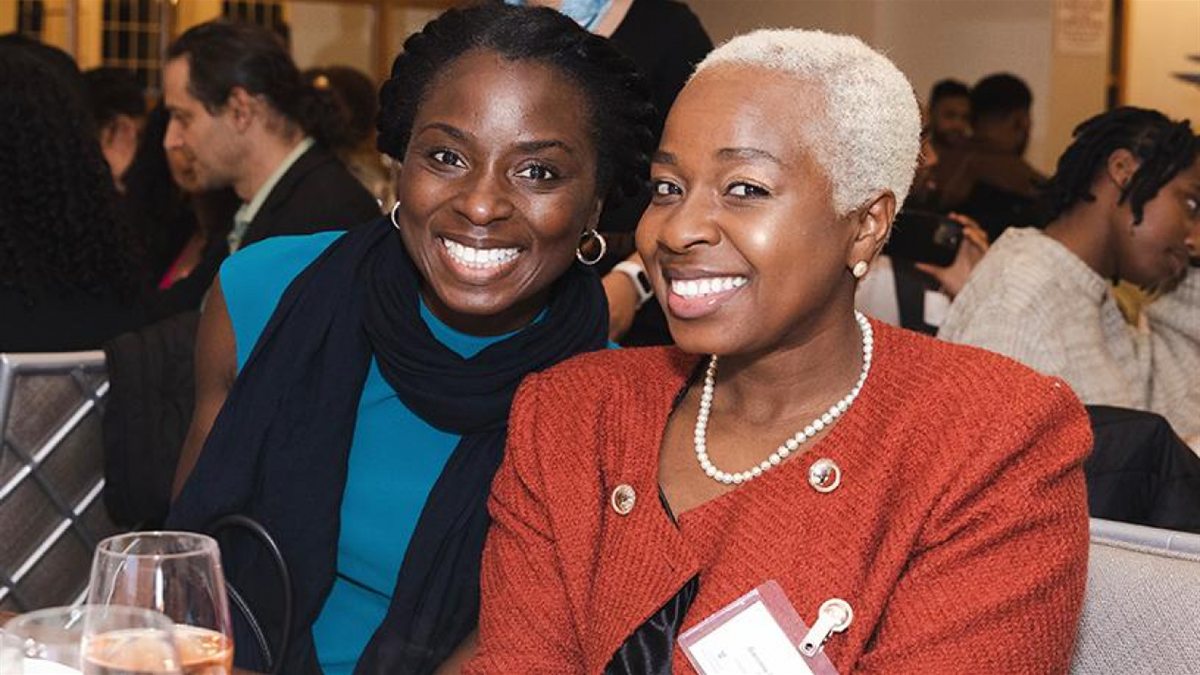 Two women smiling together at an indoor reception