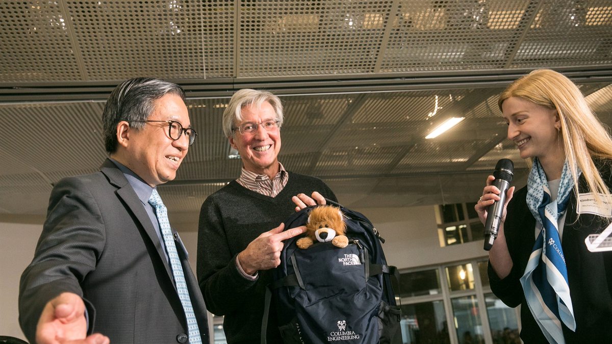 Three people standing together with a Columbia Engineering backpack at an indoor event