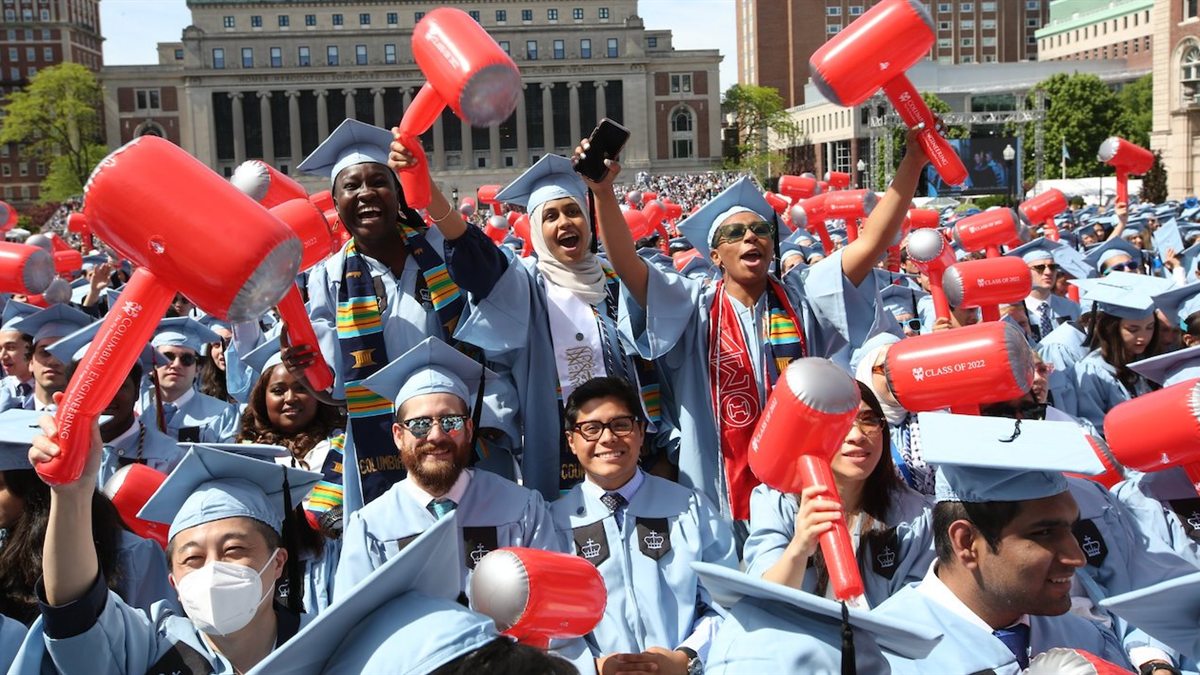 Graduates in light blue caps and gowns celebrating at commencement